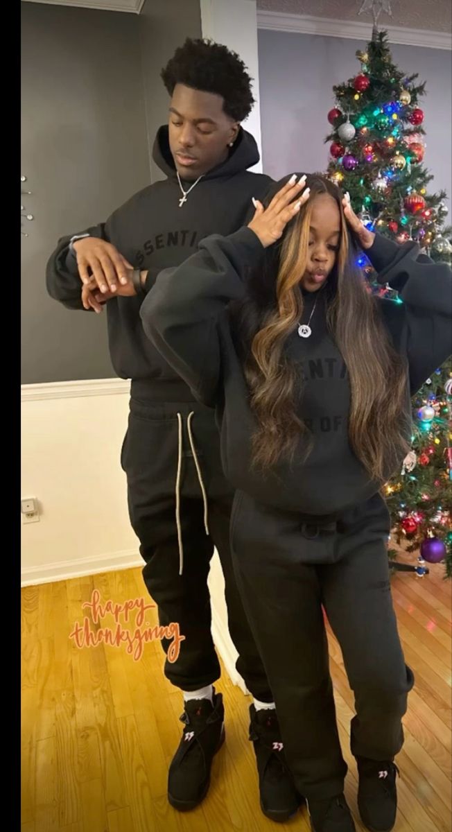 two people standing in front of a christmas tree