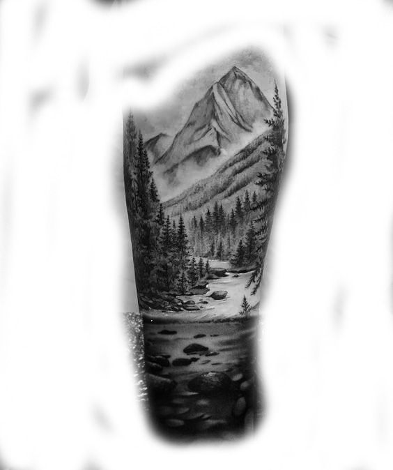 a black and white photo of a man's arm with a mountain scene on it