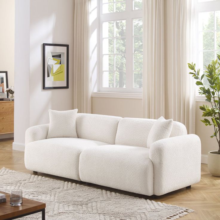 a white couch sitting in front of a window on top of a hard wood floor