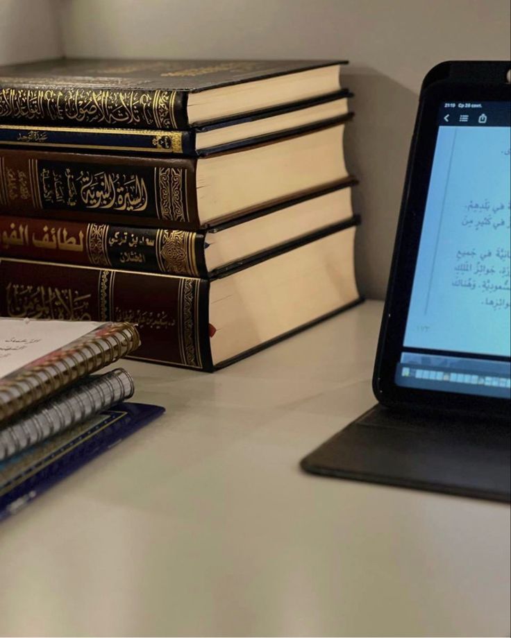 an open laptop computer sitting on top of a desk next to books and notebooks