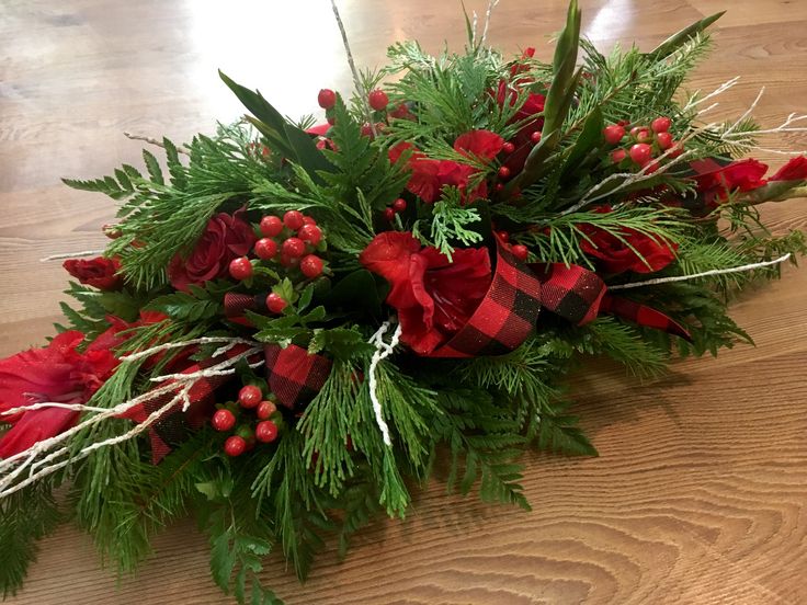 a christmas arrangement with red flowers and greenery