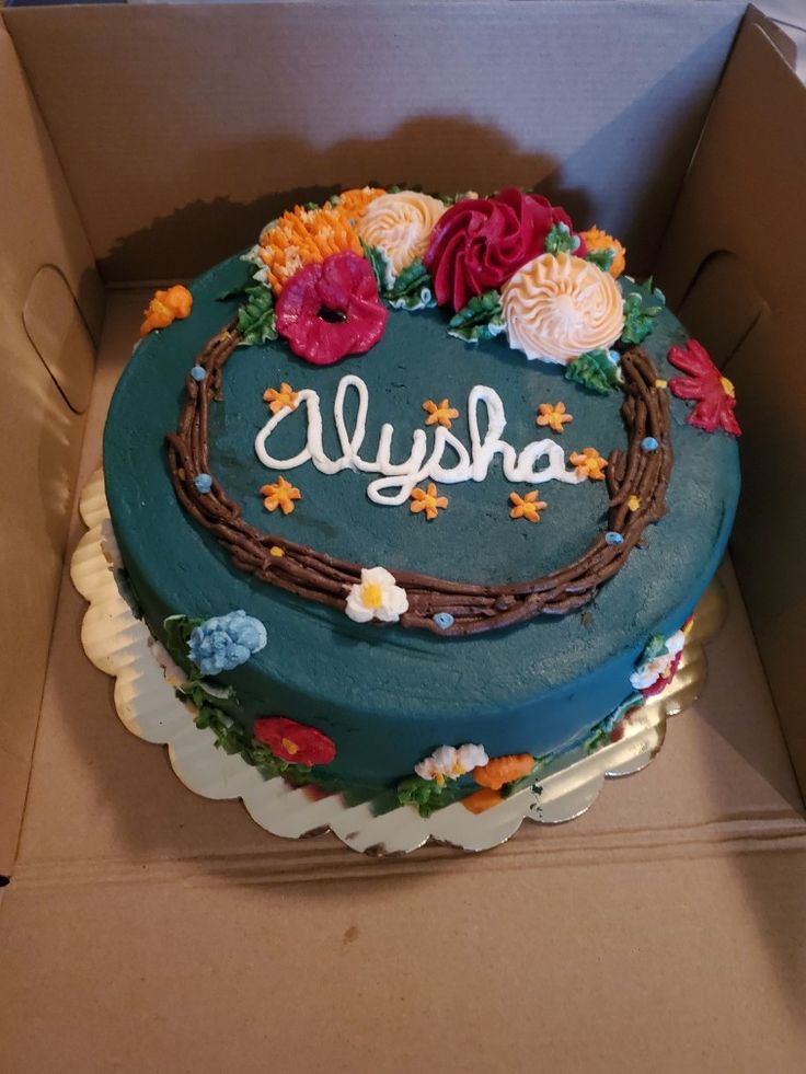 a cake in a box with the word alysha written on it and flowers