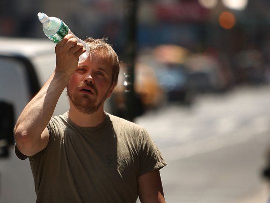 a man is walking down the street with a bottle in his hand