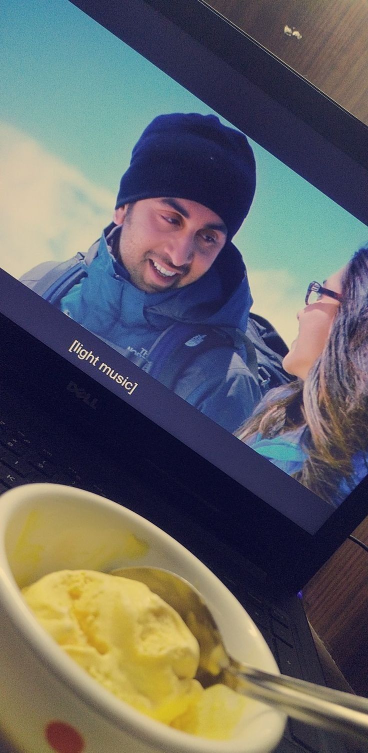 a bowl of ice cream sitting on top of a laptop computer