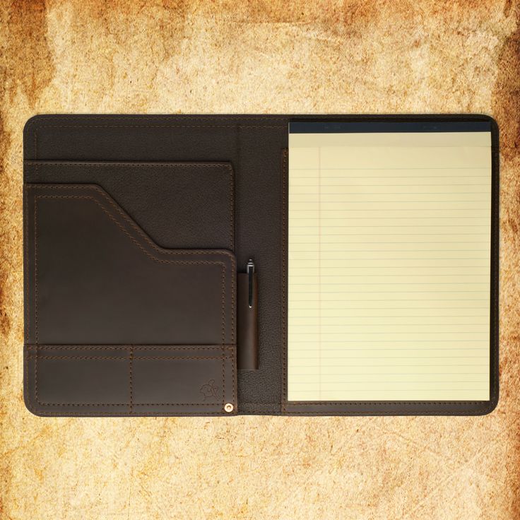 a notepad and pen on top of a brown leather folder with writing paper attached to it