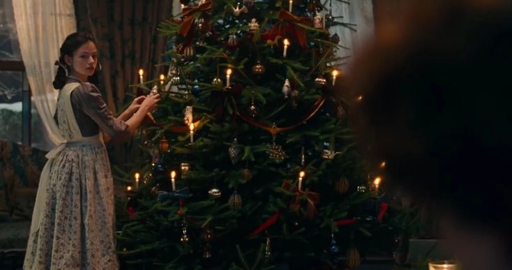 a woman standing in front of a christmas tree