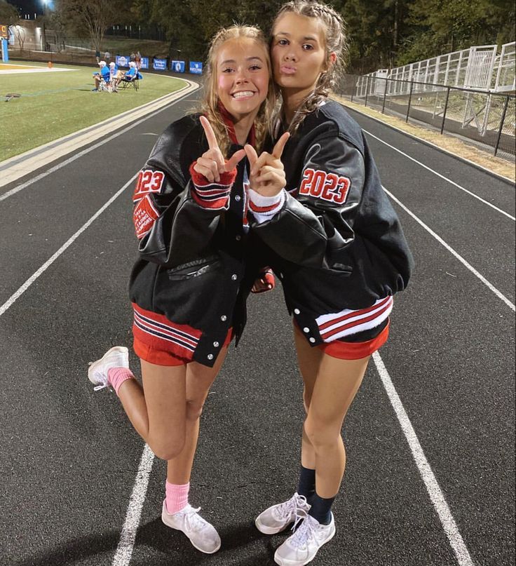 two girls standing on a track giving the peace sign