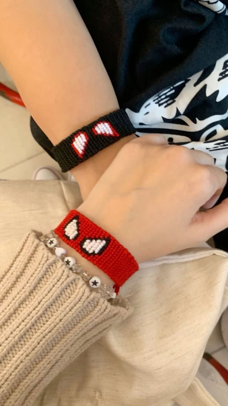 a close up of a person wearing a red bracelet with hearts on it's wrist