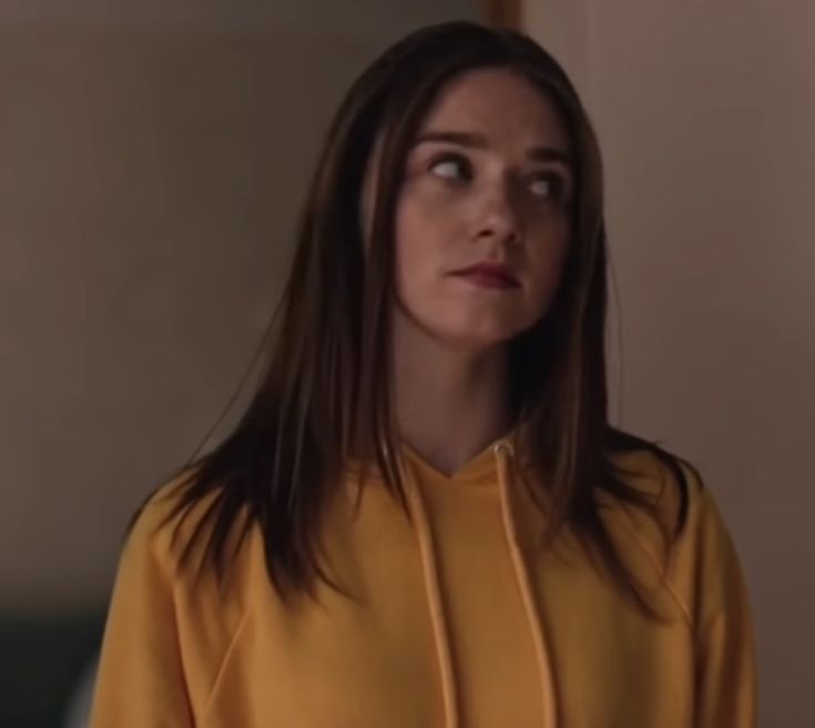 a woman with long brown hair wearing a yellow hoodie that says, at who likes me and who hates you