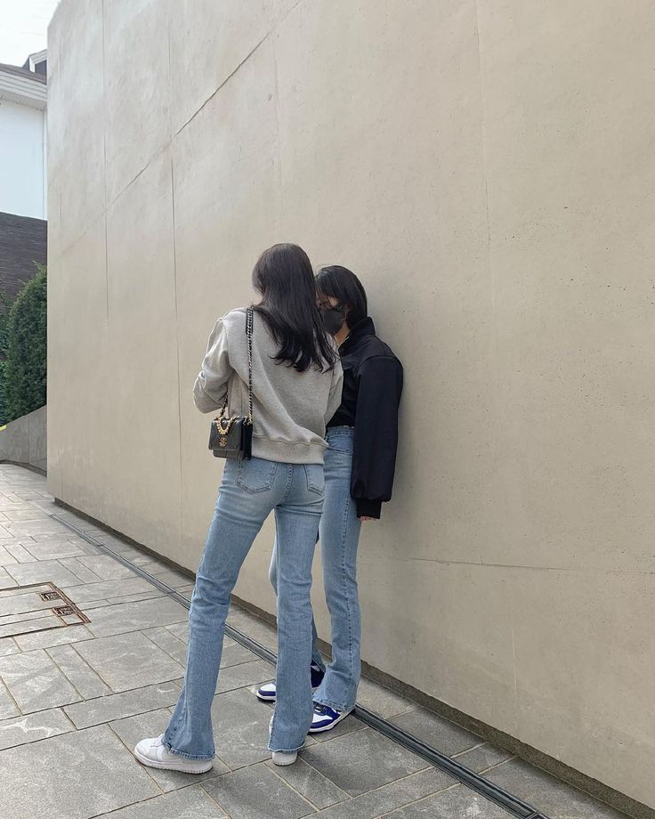 two people leaning against a wall with their backs to each other