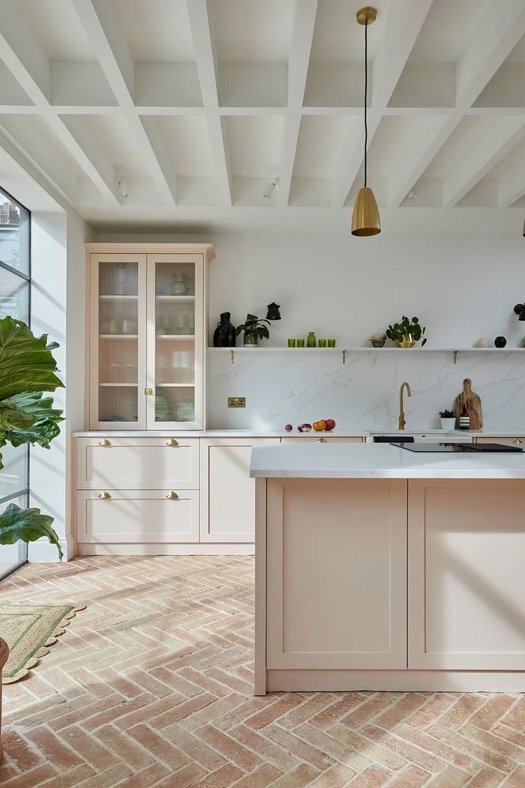 a kitchen with white cabinets and brick flooring