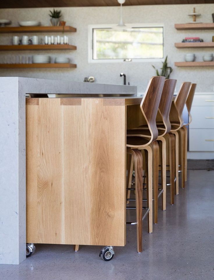 several chairs are lined up in front of an island with a sink and countertop