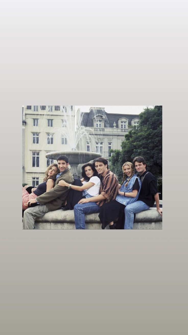 a group of people sitting next to each other near a fountain