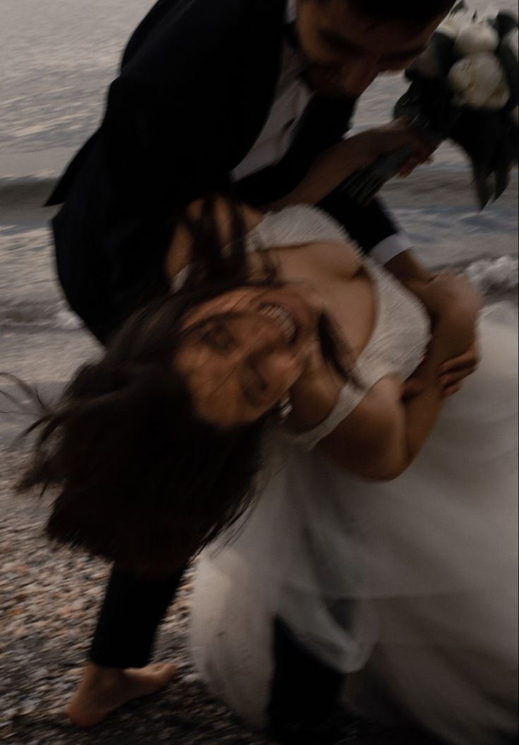 a bride and groom kissing on the beach