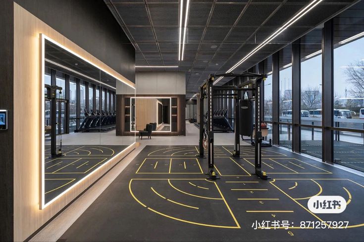 an empty gym with mirrors on the wall and equipment in the middle, along with windows