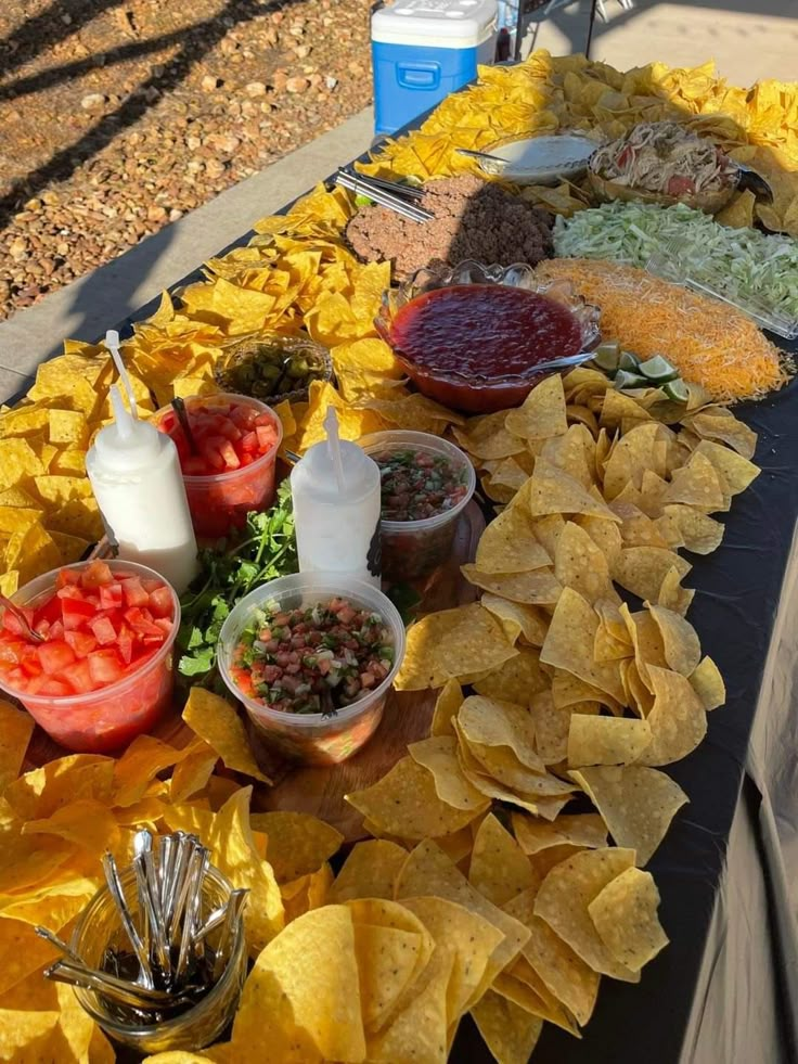 a table filled with chips, salsa and condiments on top of each other