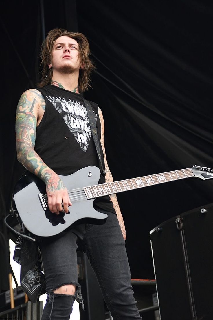 a man with tattoos on his arm playing an electric guitar in front of a stage