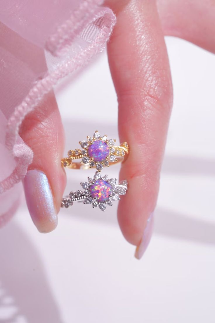 a woman's hand with two rings on her fingers and one is wearing a pink dress