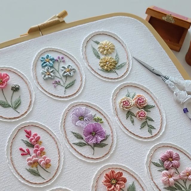 embroidery flowers are arranged in circles on a piece of white paper with scissors and thread