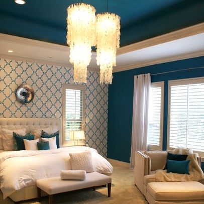 a bedroom with blue walls and white furniture in the corner, along with chandelier