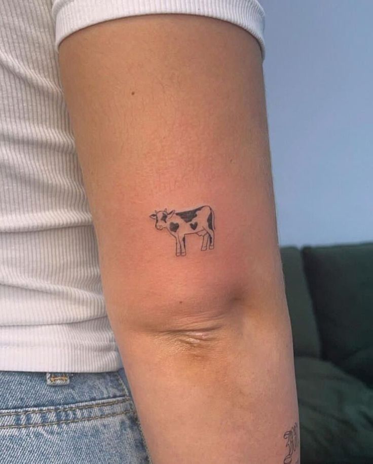 a small cow tattoo on the left side of the right arm, it is black and white