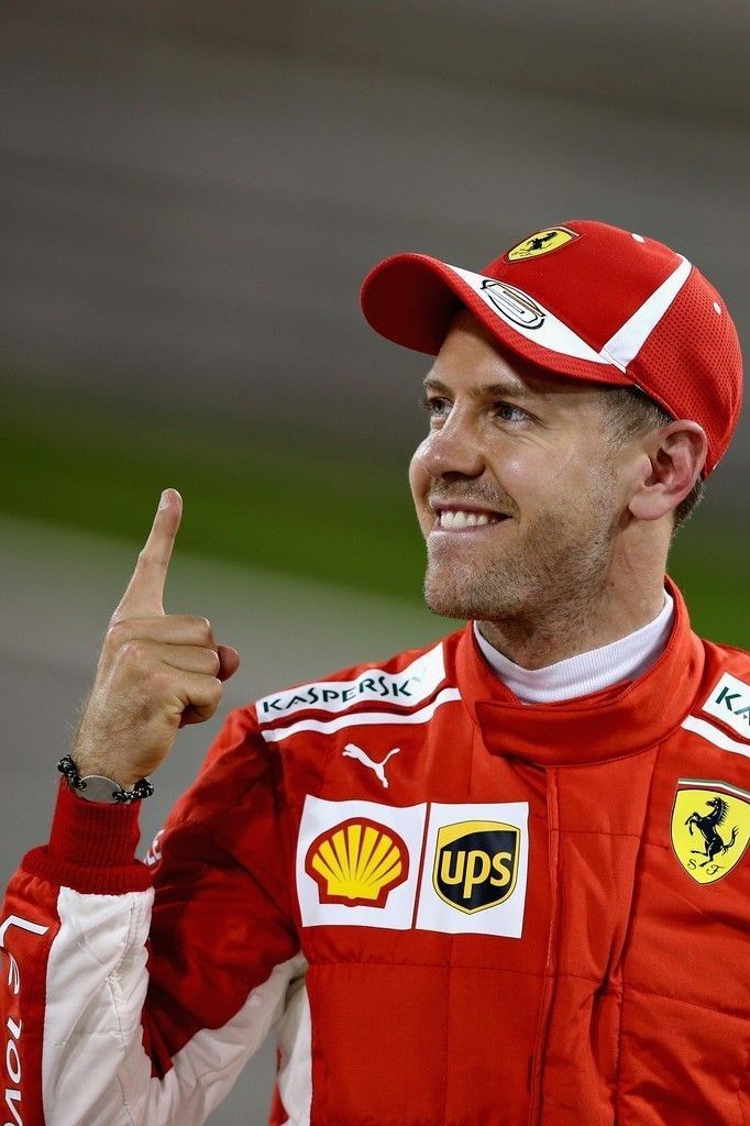 a man in a red racing suit giving the peace sign