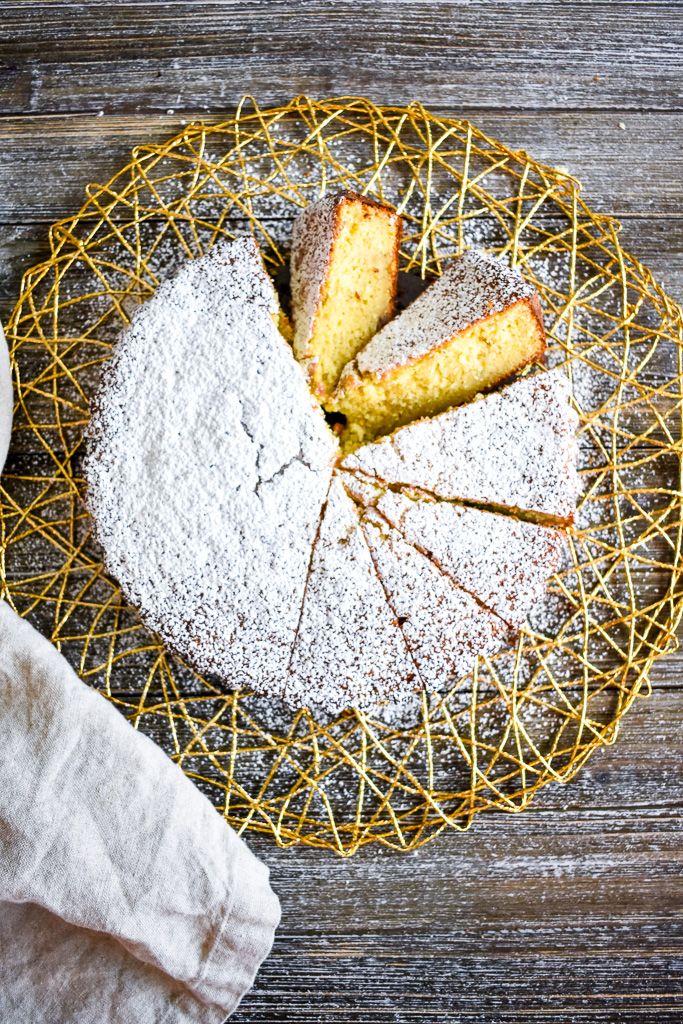 a cake with powdered sugar on top sits in a wire basket next to a napkin