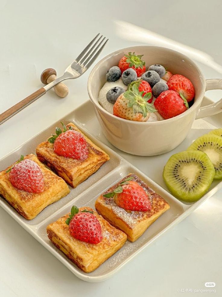 fruit and pastries are on trays next to a bowl of strawberries, kiwi