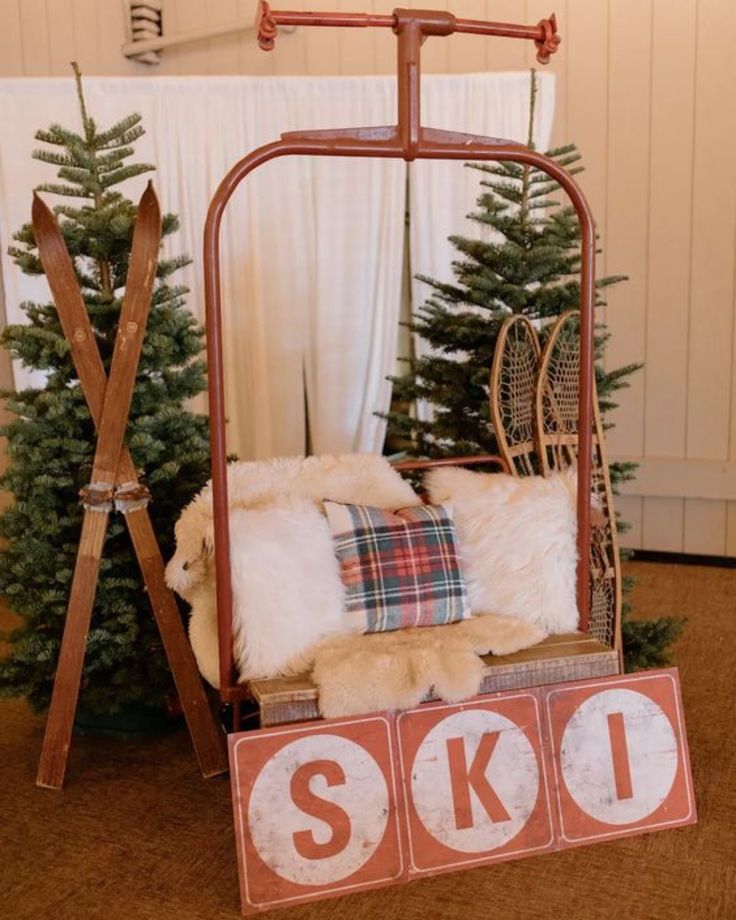 an old fashioned swing chair with skis and pillows on the floor next to a christmas tree