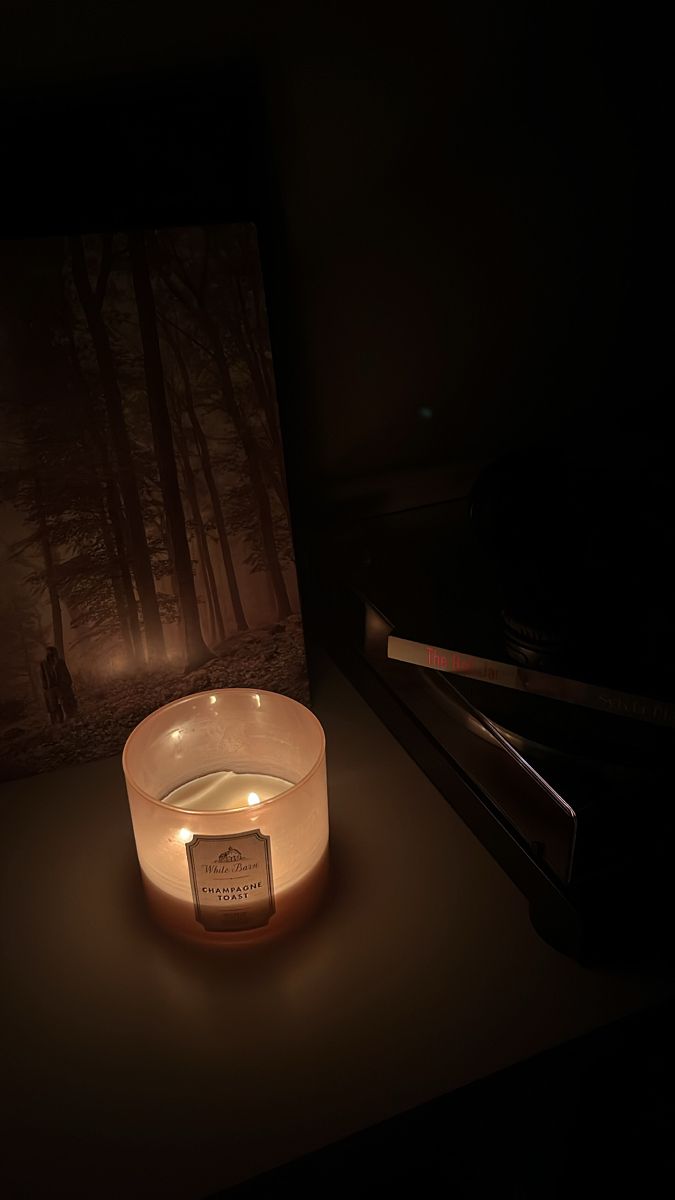 a lit candle sitting on top of a table next to a framed photo and piano