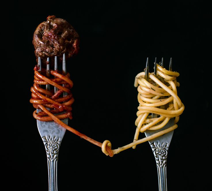 two forks with different types of food on them, one being eaten by the other