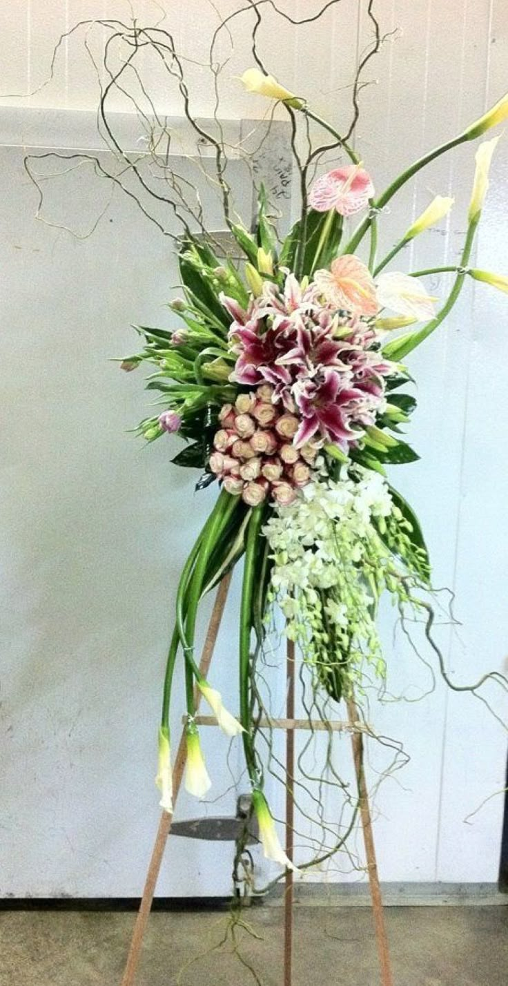 a tall vase with flowers and greenery in it