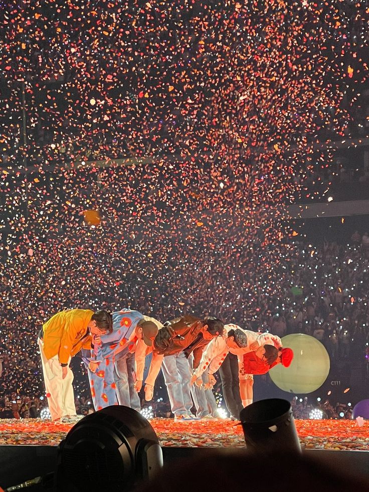 a group of people standing on top of a stage with confetti in the air