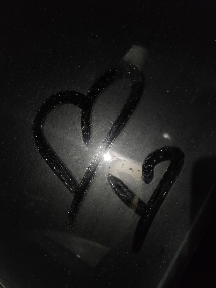 the word love is written in black ink on a metal surface with water droplets around it