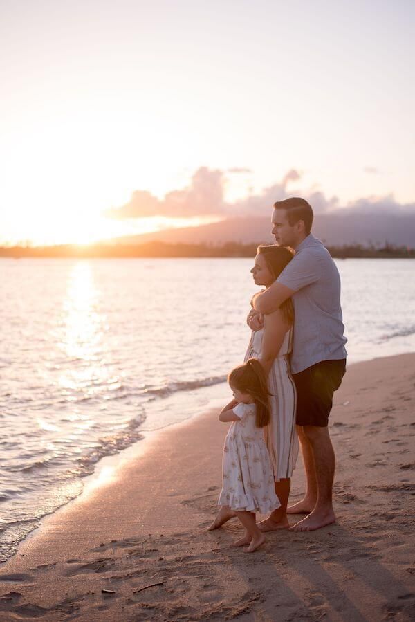 a family standing on the beach at sunset