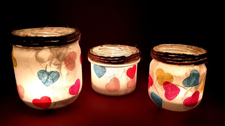 three jars with hearts painted on them sitting next to each other in front of a black background