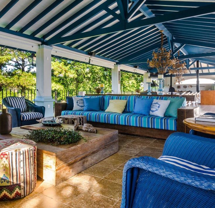 an outdoor living area with blue and white striped chairs, couches, tables and coffee table