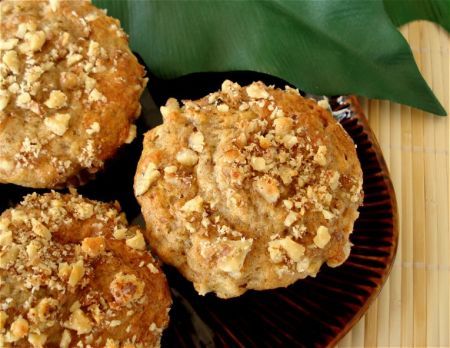 three muffins sitting on top of a black plate next to a green leaf