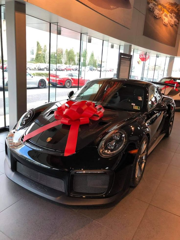 a black sports car with a red bow on it's hood in a showroom