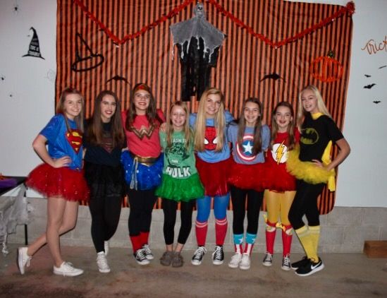 a group of young women standing next to each other in front of a halloween decoration