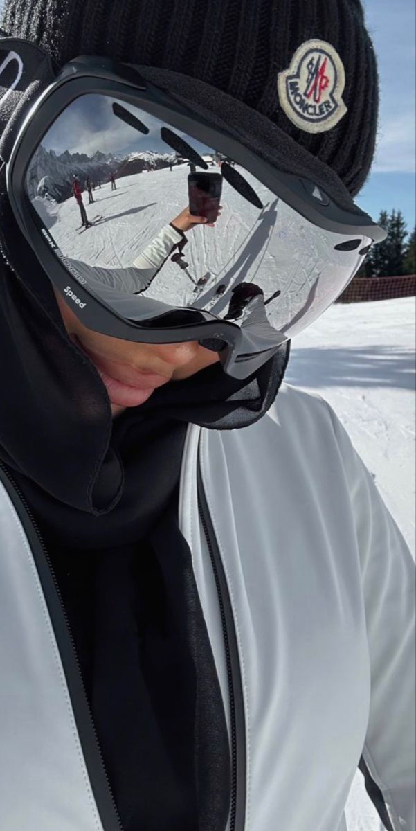 a man wearing ski goggles is taking a selfie in the mirror while snowboarding