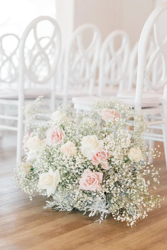 a bouquet of flowers sitting on top of a wooden floor next to white rocking chairs