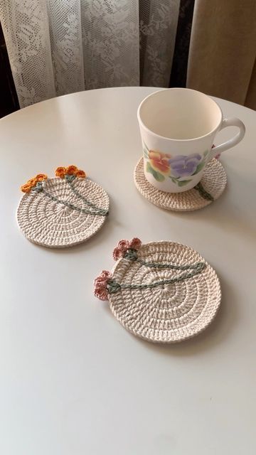 two plates with flowers are sitting on a table next to a cup and saucer