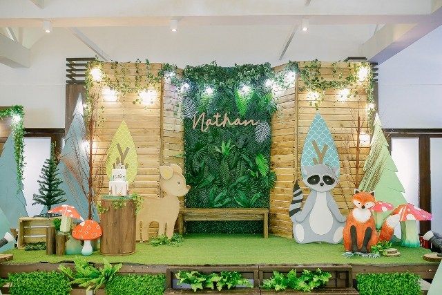 a stage set up for a children's birthday party with animals, trees and plants