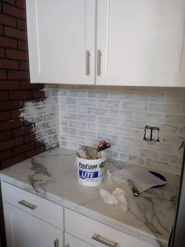 a bucket full of toilet paper sitting on top of a counter next to white cabinets