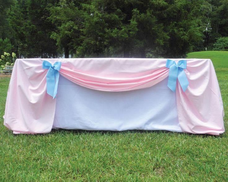 a pink and white table cloth with blue bows on the top is set up for an outdoor ceremony