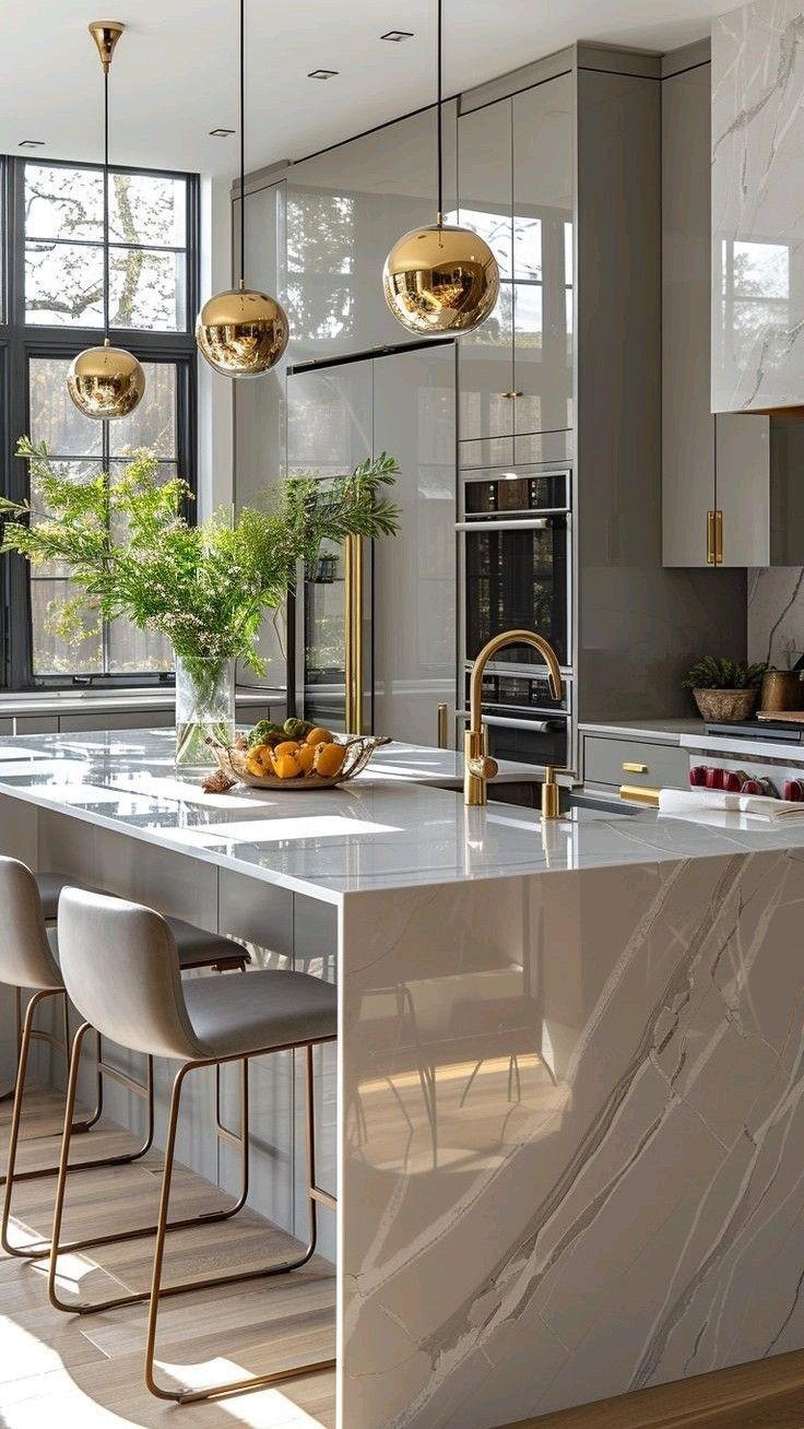 a large kitchen with marble counter tops and gold pendant lights hanging from the ceiling over the island