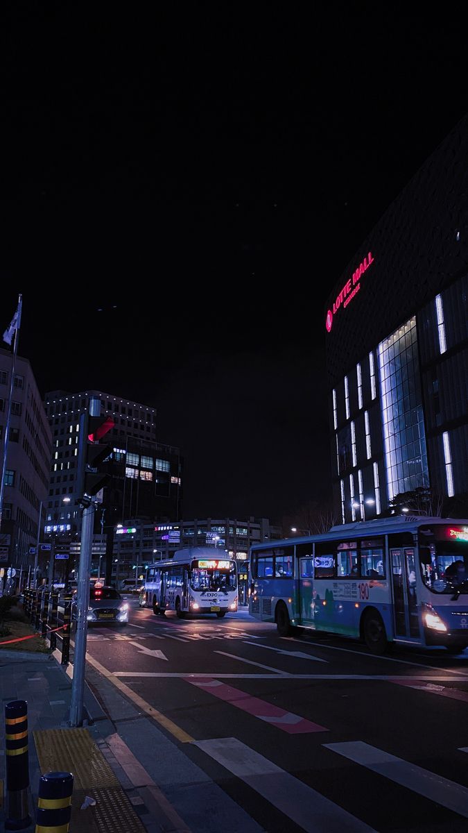 a city street at night with buses and buildings