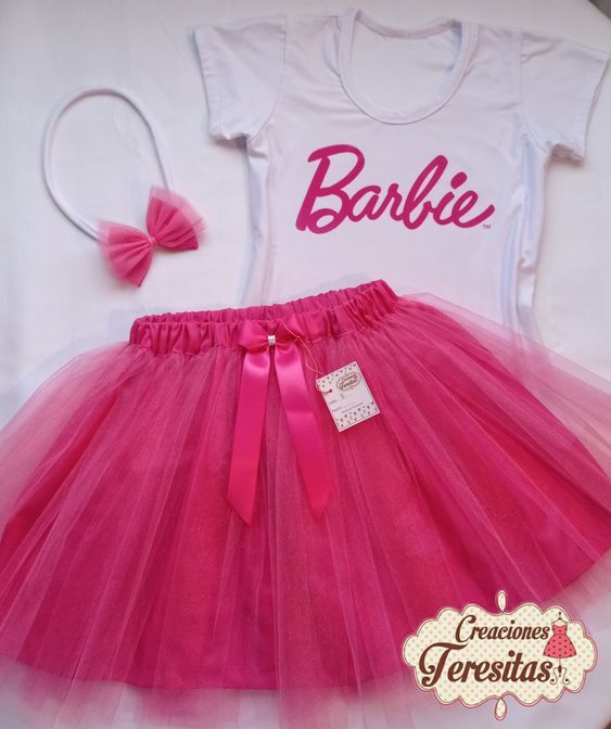 a pink tutu skirt and white shirt with the name barbie on it, sitting next to a headband