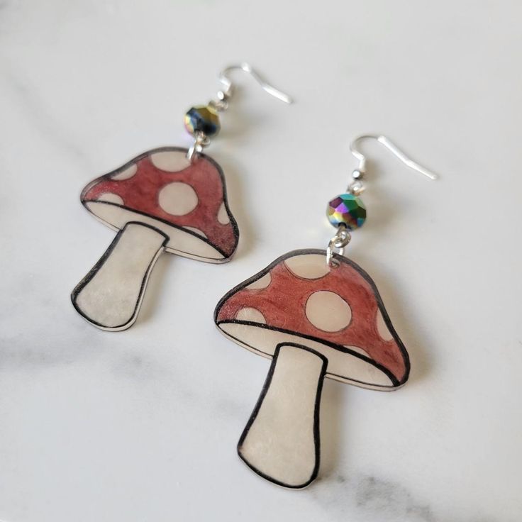 a pair of earrings with red and white mushrooms on them